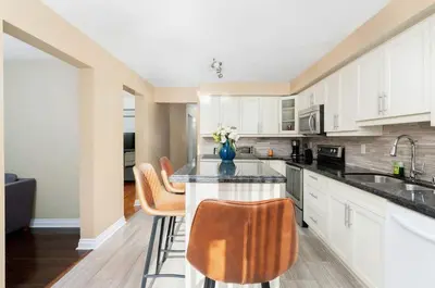 a kitchen with white cabinets and a table with chairs at House with 5 Beds for Families in Great Location in Mississauga