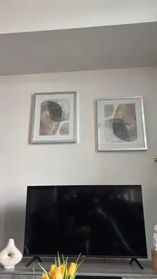 a flat screen tv in a living room with two pictures at apartment for 2 by water in St. Catharines