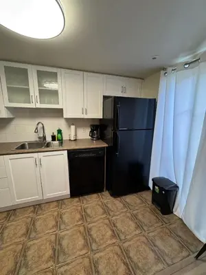 a kitchen with a black refrigerator and white cabinets at Small Apartment for 2 in St. Catharines