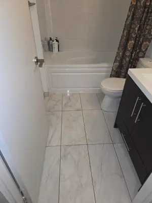 a bathroom with a tub and a toilet and a sink at Condo with grey sofa bed in Port Hope