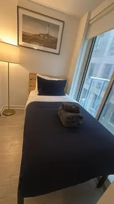 a bedroom with a bed and a large window at Condo with grey sofa bed in Port Hope