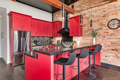 a kitchen with red cabinets and a brick wall at The Brick & Beam Boutique Hotel in Collingwood