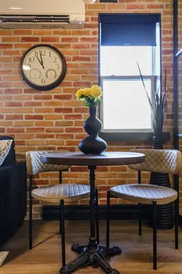 a clock on a brick wall with a table and two chairs at The Brick & Beam Boutique Hotel in Collingwood