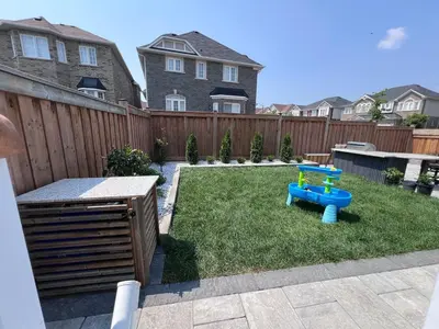 a backyard with a blue table in the grass at Luxury 2 Bedroom 2Bathroom Modern B Apartment in Ajax, Toronto in Ajax
