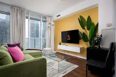 a living room with a green couch and a tv at Live the excitement Stay next to Scotiabank Arena! in Toronto