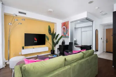 a living room with a green couch and a tv at Live the excitement Stay next to Scotiabank Arena! in Toronto