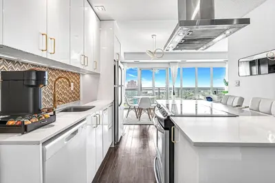 a kitchen with white cabinets and a large window at Charming lakeview suite with parking in Toronto