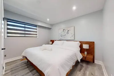 a white bedroom with two beds and a window at 10 Acre Farmhouse with Pool + 5 Bedrooms/3 Baths in East Gwillimbury