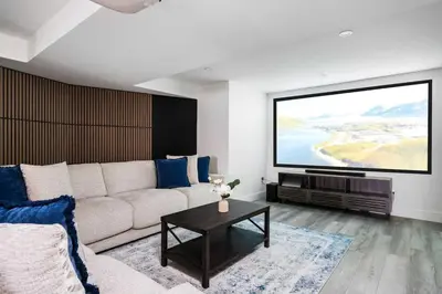 a living room with a couch and a large screen at Large chalet 3 King bed Sauna-Hot Tubs Projector in Blue Mountains