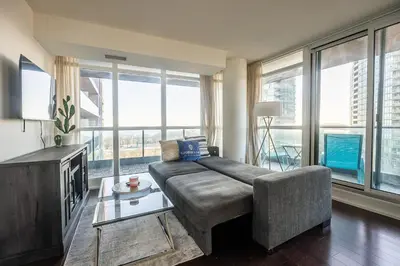 a living room with a couch and large windows at Panoramic 2 Bedroom Condo with Terrace Fort York Downtown Toronto in Toronto