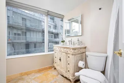 a bathroom with a toilet and a sink and a window at Centrally located 2 Bd 2 Bth + Parking in Toronto
