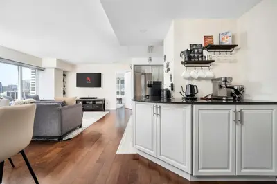 a kitchen with white cabinets and a living room at Centrally located 2 Bd 2 Bth + Parking in Toronto