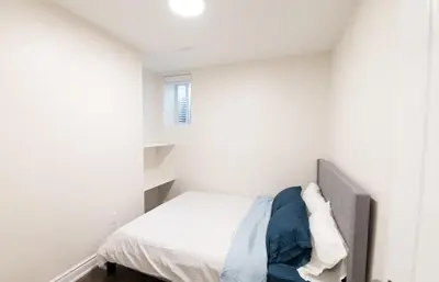 a bedroom with a bed in a white room at New Basement Apartment with parking in Oakville