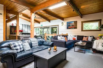 a living room with a leather couch and a table at Cozy upgraded Chalet Hot Tubs Sauna Fireplace in Blue Mountains