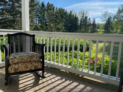 a chair on a porch with a fence and flowers at Beaver Valley Farmhouse with Pool & Stunning Views in Kimberley