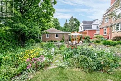 a garden in front of a house with flowers at Warm, Stylish Edwardian Escape in Downtown Meaford in Meaford
