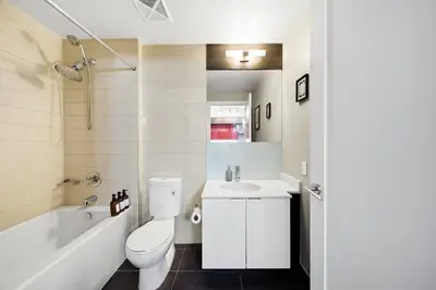 a white bathroom with a toilet and a sink at Modern City Condo with Parking Walk to CN Tower in Toronto