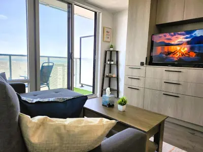 a living room with a tv and a couch and a table at Toronto Lakeview by TMU & UofT with Pool, Gym & Parking in Toronto