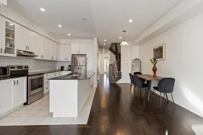 a kitchen with white cabinets and a table and chairs at Serenity Home in Brampton in Brampton