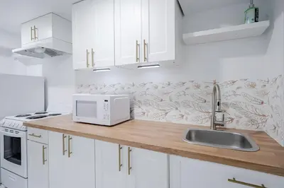 a white kitchen with a sink and a microwave at Bright Modern 1BR Suite Kitchen Workspace Smart TV in Bowmanville