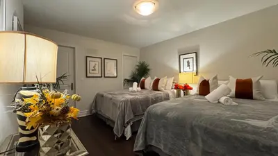 a bedroom with two beds and a lamp and flowers at Executive Luxury Stay Corporate Paradise in South Richvale in Richmond Hill