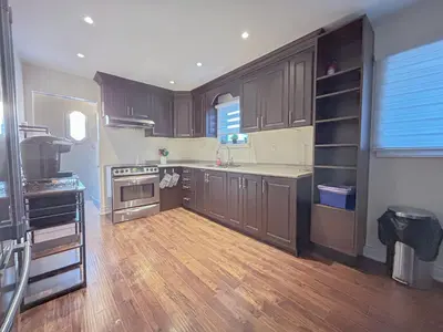 a kitchen with brown cabinets and a wooden floor at Executive Urban Retreat in Brampton