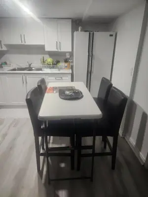a kitchen with a table with chairs and a refrigerator at A very peaceful home in Oshawa