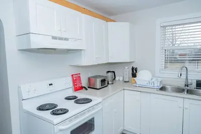 a white kitchen with a stove and a sink at Cozy Bungalow Near Niagara Falls - Perfect Family Retreat in Niagara Falls