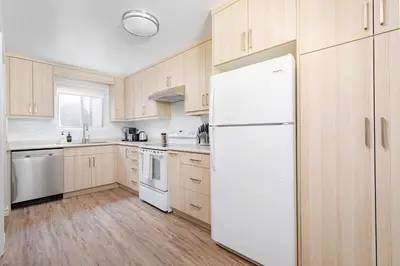 a white refrigerator in a kitchen with wooden cabinets at Charming 4 Bed Home + 2Parking in Toronto
