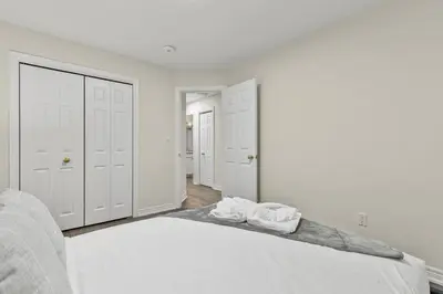 a white bedroom with a bed with two towels on it at Chelsea Suite 3BR, 1B with parking for 28plus stays in St. Catharines