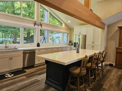 a kitchen with white cabinets and a large island with bar stools at Olga's Bay Lakehouse in Minett