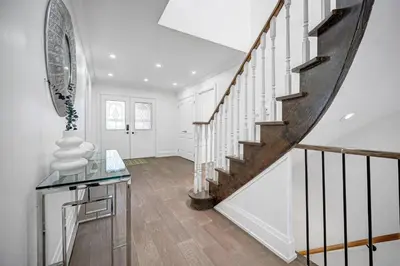 a white hallway with a staircase with a glass table at 166 Main - Family Getaway 5BR Home with Backyard & Parking in Markham