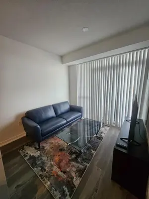a living room with a blue couch and a glass table at Luxury 2 Bed Apartment In Vaughan Near Wonderland! in Vaughan
