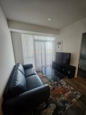a living room with a black leather couch and a television at Luxury 2 Bed Apartment In Vaughan Near Wonderland! in Vaughan