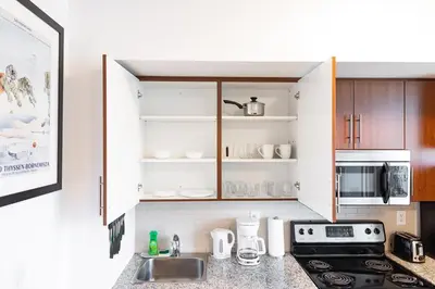 a kitchen with white cabinets and a sink and a stove at Downtown Toronto CN Tower Condo in Toronto