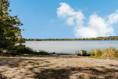 a boat sitting on the shore of a lake at Lakefront Englewood Villas Private BBQ and Lakeview in Lakefield