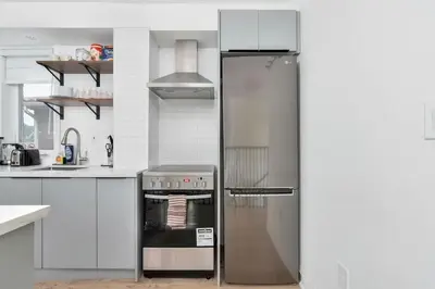 a stainless steel refrigerator in a white kitchen at Chic 3BR Ossington Hub Near Subway & Shops in Toronto