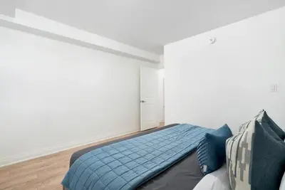 a bedroom with a bed with a blue blanket at Chic 3BR Ossington Hub Near Subway & Shops in Toronto
