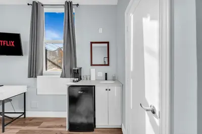 a white kitchen with a black refrigerator and a window at Guestic at Queen West in Toronto