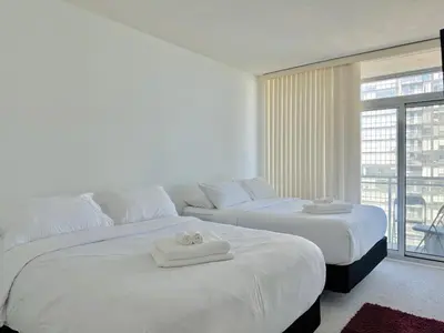 two white beds in a room with a balcony at Dreamspace 3 Bdrms with 1 Parking in Toronto