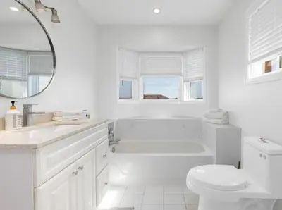 a white bathroom with a tub and a toilet at Bright 3BR Home in Richmond Hill free parking in Richmond Hill