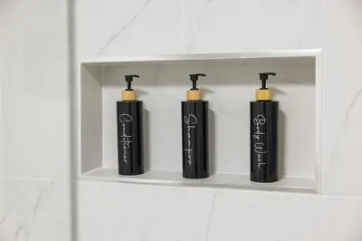 three black bottles sitting on a shelf in a bathroom at Large Studio Room No 1 in North York in Toronto