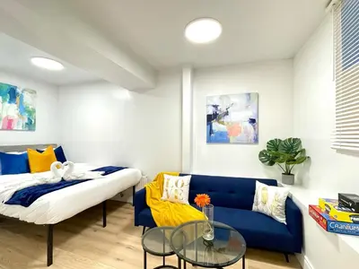 a living room with a blue couch and a glass table at The Scholar Suite Modern Comfort Near Western U in London