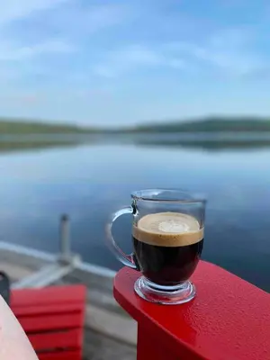 a cup of coffee sitting on a red table at Rustic and Spacious Lakefront Oasis in Nature in Algonquin Highlands