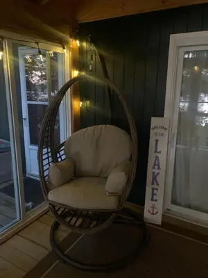 a wicker rocking chair sitting on a porch at Rustic and Spacious Lakefront Oasis in Nature in Algonquin Highlands