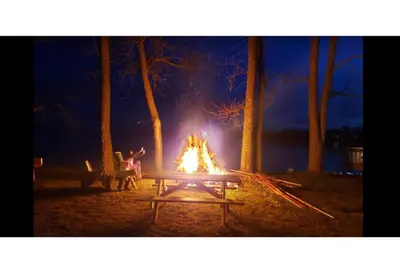 a picnic table with a fire at night at Sandbanks Beach Cottage in West Lake