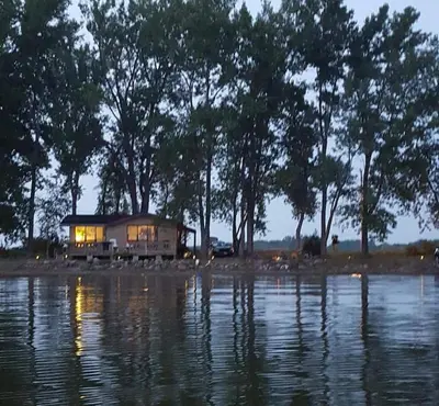 a house sitting on the shore of a body of water at Sandbanks Beach Cottage in West Lake