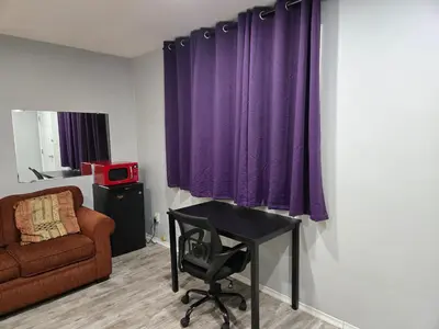 a room with a chair and a desk and purple curtains at Cobourg Inn in Cobourg