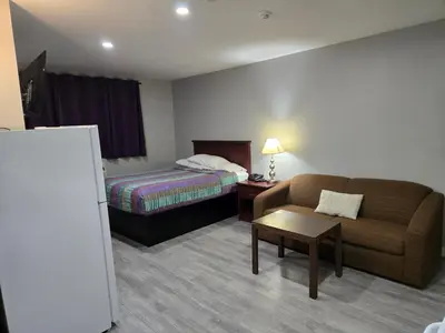 a hotel room with a couch and a bed at Cobourg Inn in Cobourg