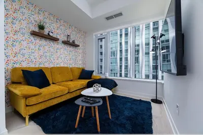 a living room with a yellow couch and a table at Stylish Yorkville Condo Sleeps 3 Prime Location in Toronto